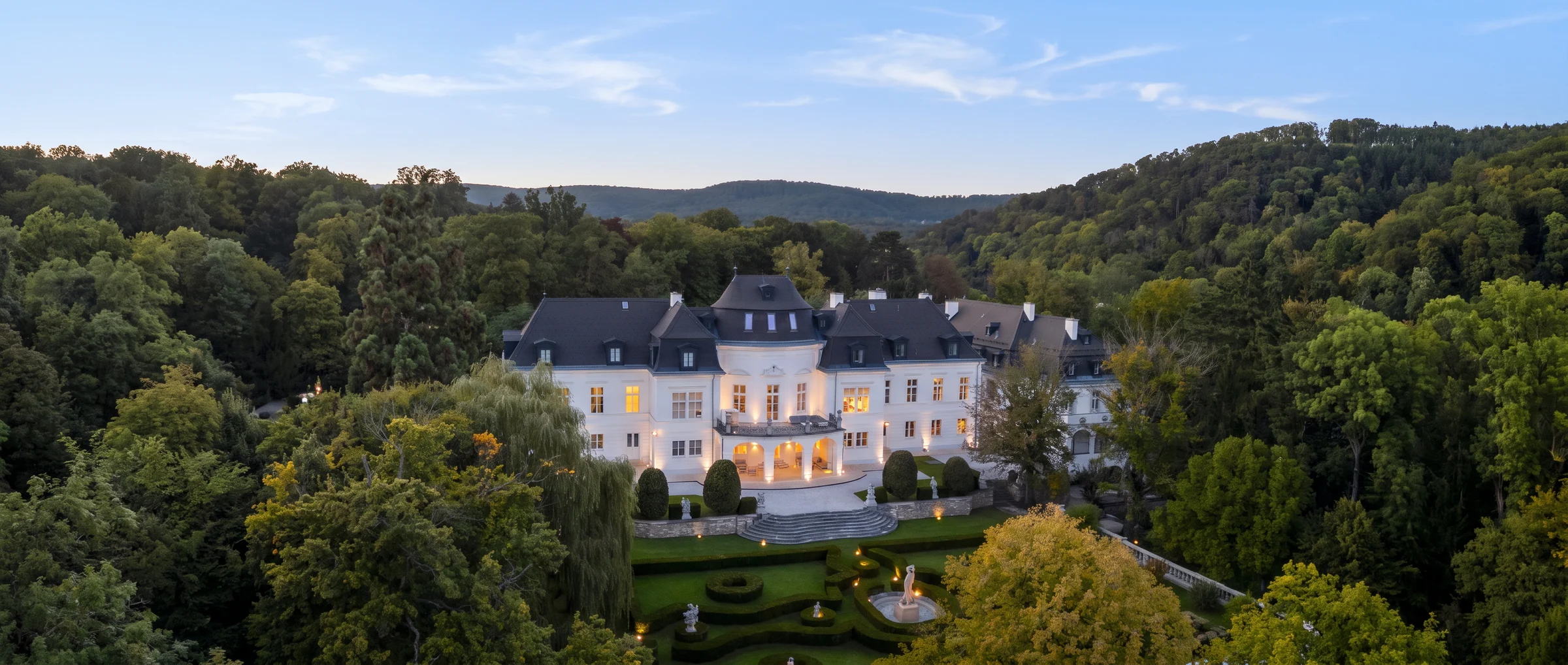 Palacete histórico iluminado al atardecer rodeado de bosque en las afueras de Viena